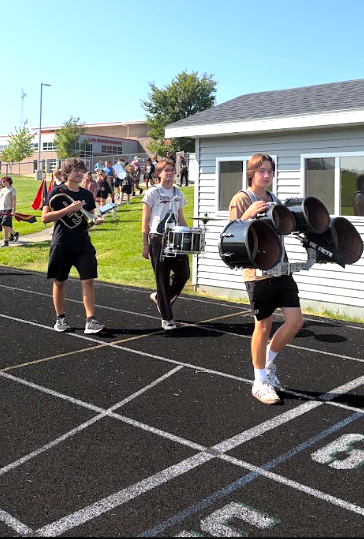 MHS Band Camp students playing instruments, practicing the halftime routine on the football field, and marching