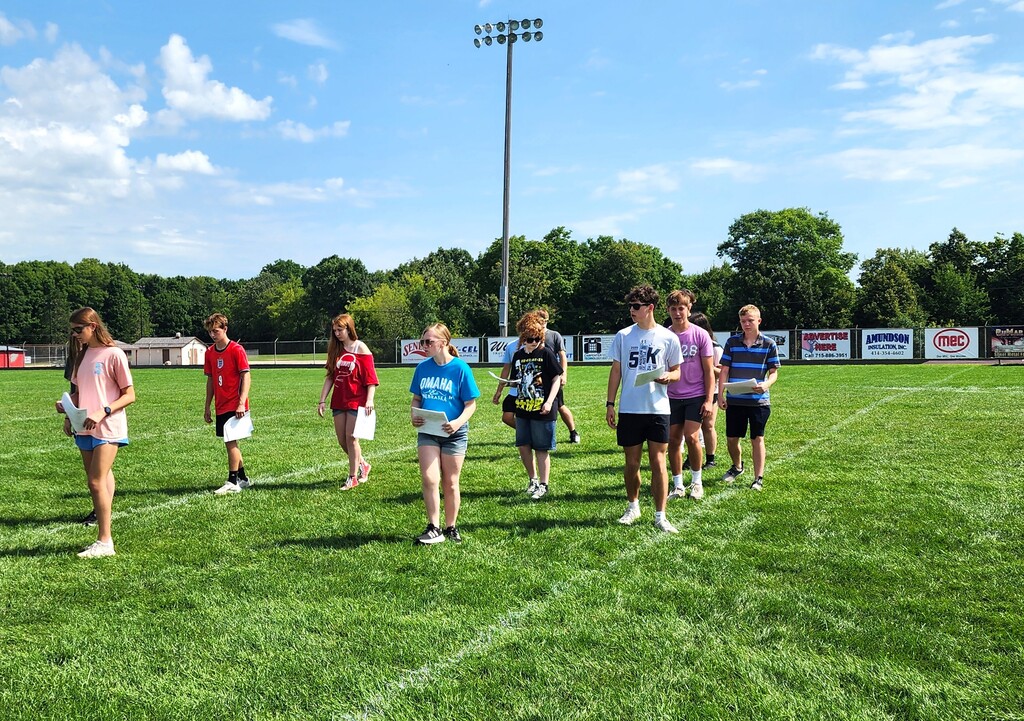 MHS Band Camp students playing instruments, practicing the halftime routine on the football field, and marching