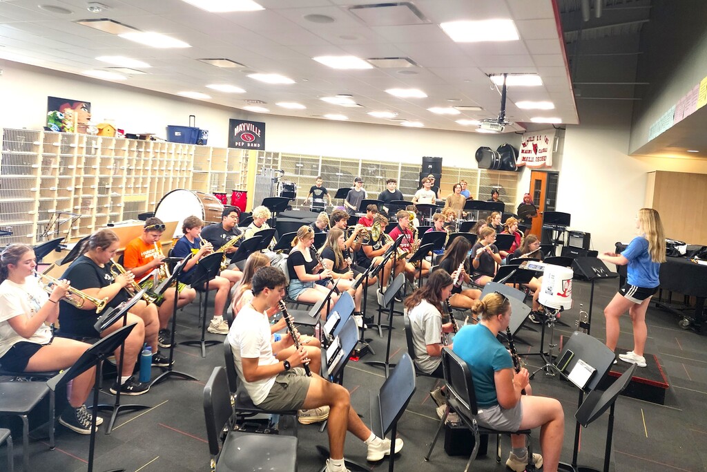 MHS Band Camp students playing instruments, practicing the halftime routine on the football field, and marching