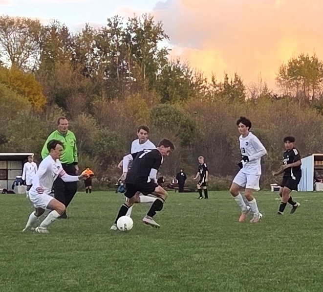 MHS Boys Soccer vs. Lake Mills at home final regular season game 10/16/26 student athletes playing on sunny soccer field with fall background