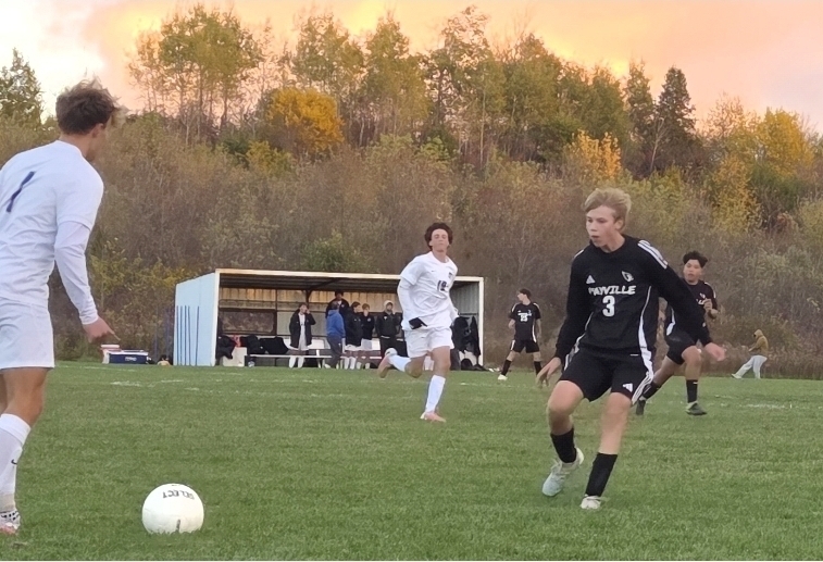 MHS Boys Soccer vs. Lake Mills at home final regular season game 10/16/26 student athletes playing on sunny soccer field with fall background