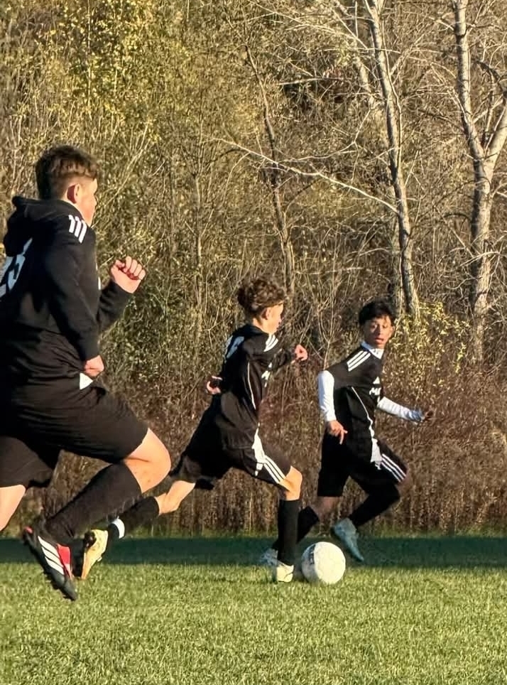 MHS Boys Soccer vs. Lake Mills at home final regular season game 10/16/26 student athletes playing on sunny soccer field with fall background