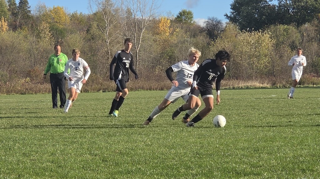 MHS Boys Soccer vs. Lake Mills at home final regular season game 10/16/26 student athletes playing on sunny soccer field with fall background