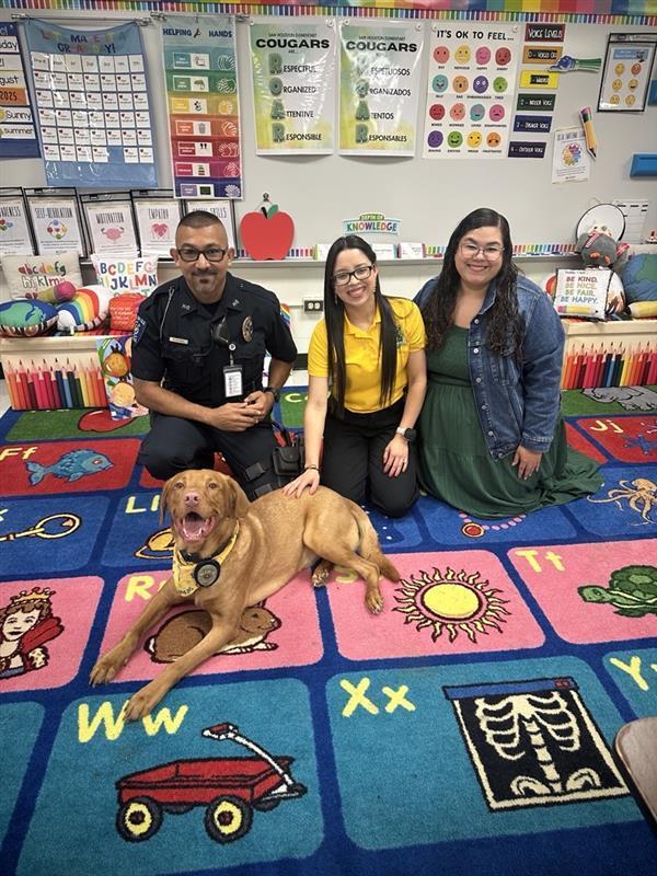 Adults posing with Buddy, the district therapy dog.