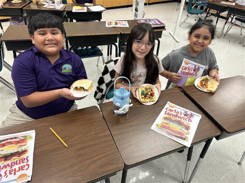 Kids posing with book and sandwich.