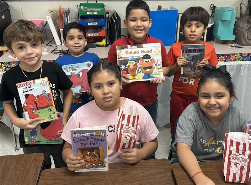 Kids posing with book and popcorn.