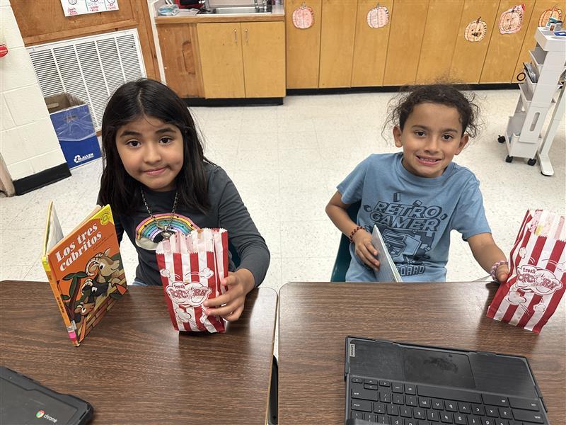 Kids posing with book and popcorn.
