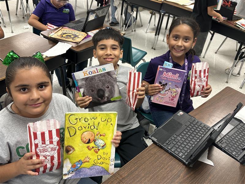 Kids posing with book and popcorn.