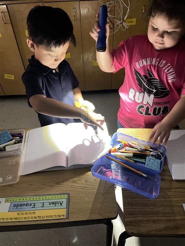Students using a flashlight to create shadows.