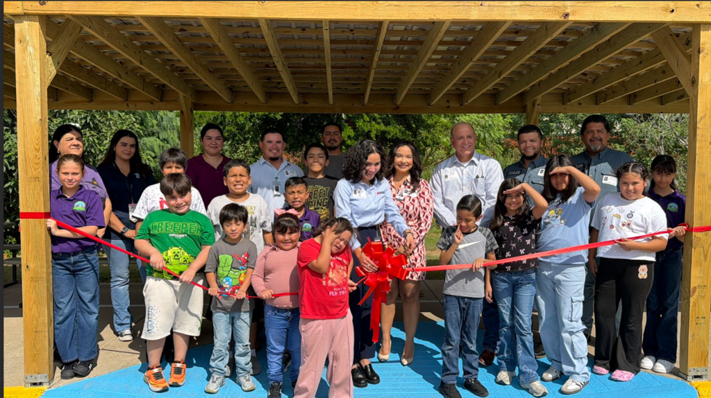 Adult cutting ribbon with others posing.