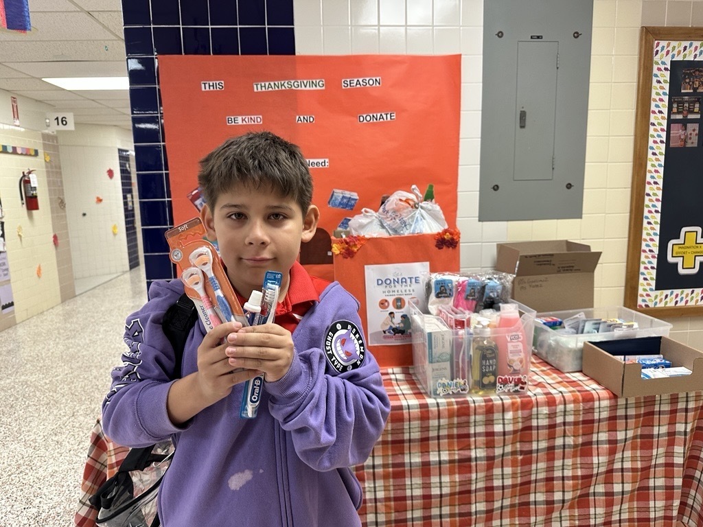 Student holding up donations for care packages.