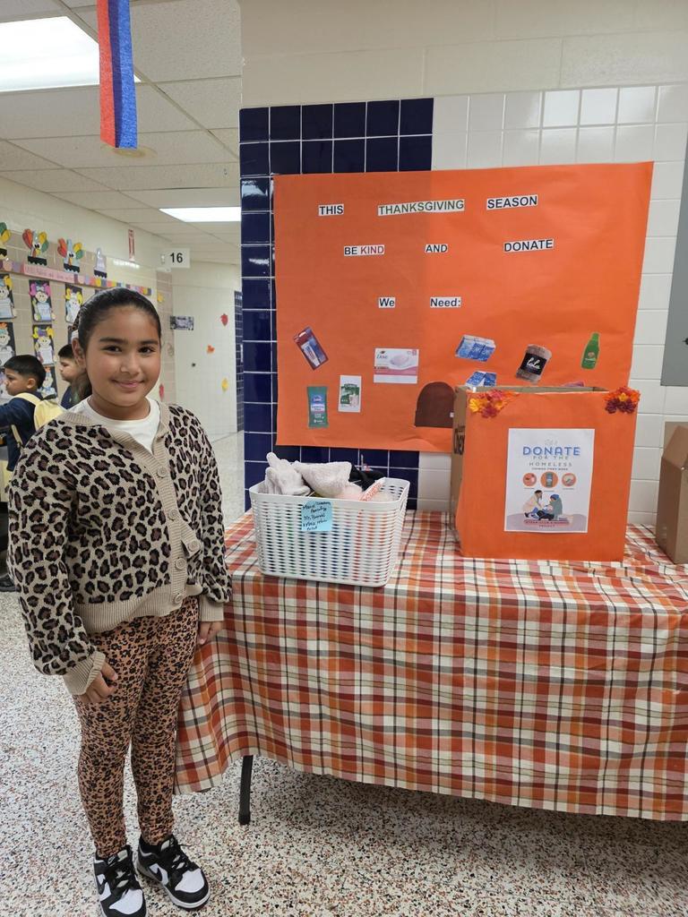 Student smiles next to care package donation table.