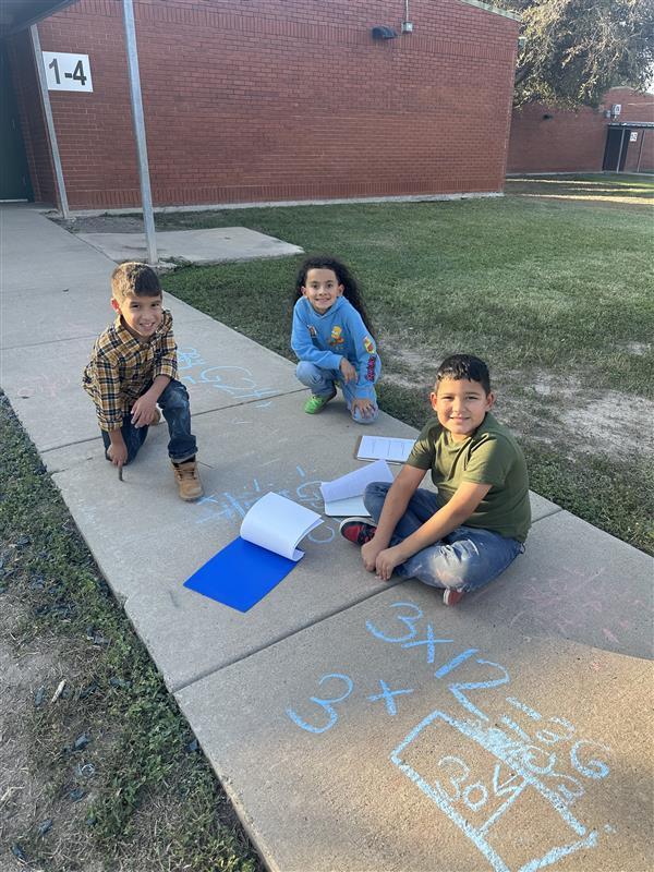 Kids posing while working on multiplication facts outside.