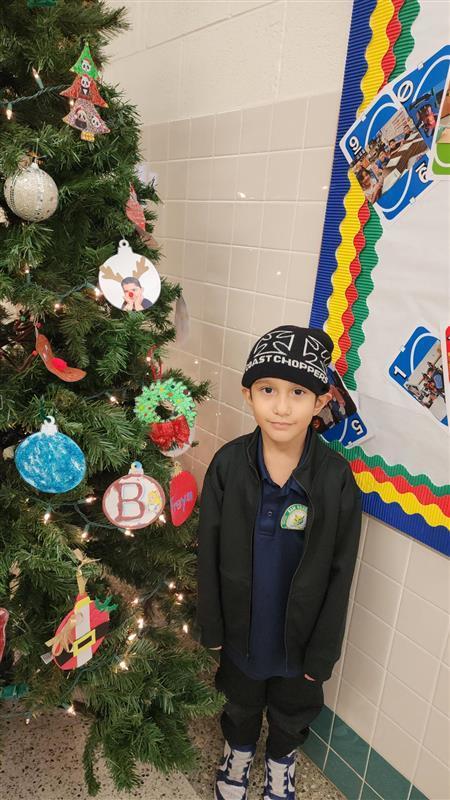 Student posing in front of Christmas tree.