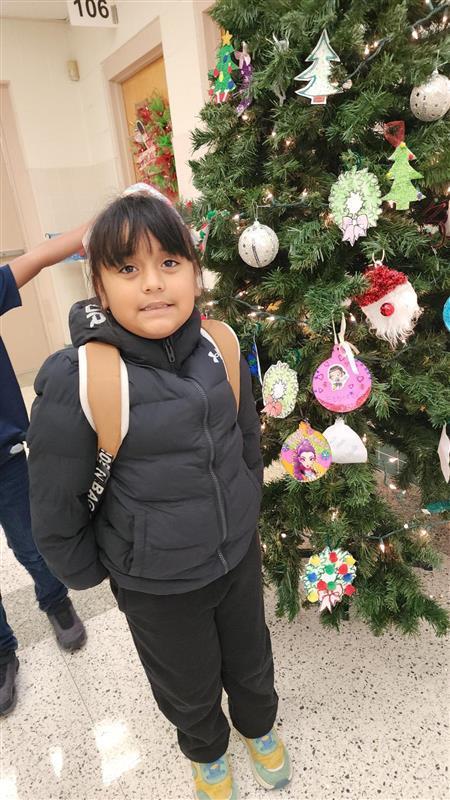 Student posing in front of Christmas tree.