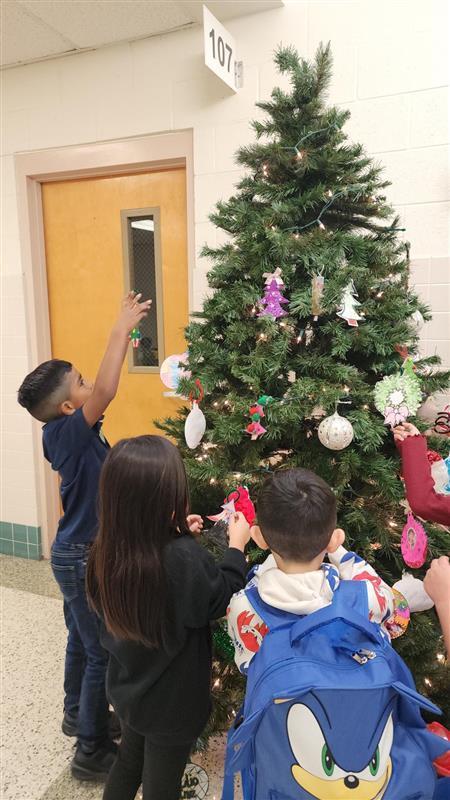 Students putting ornaments on Christmas tree.