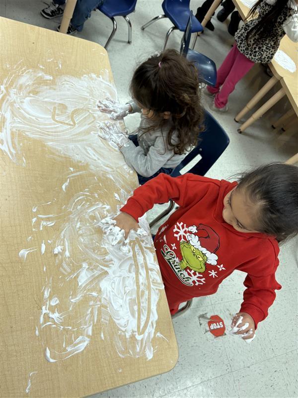 Student working on letters and numbers with shaving cream.