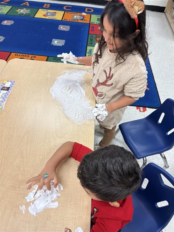 Student working on letters and numbers with shaving cream.