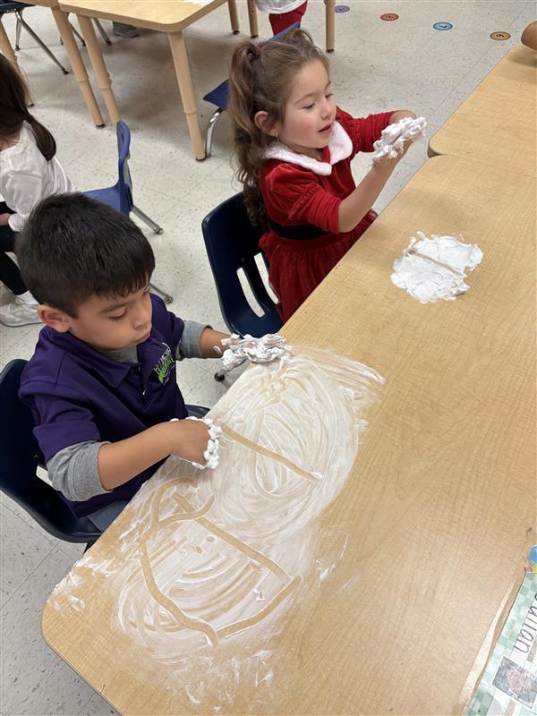 Student working on letters and numbers with shaving cream.