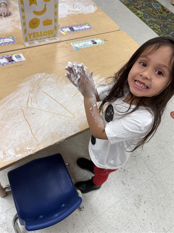 Student working on letters and numbers with shaving cream.