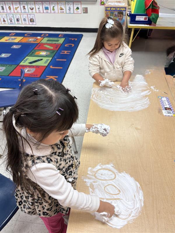 Student working on letters and numbers with shaving cream.