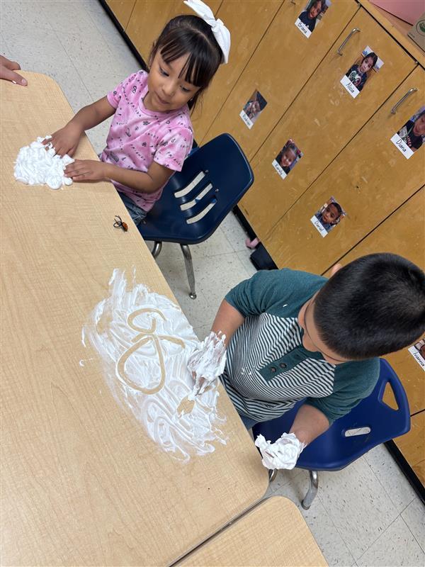 Student working on letters and numbers with shaving cream.