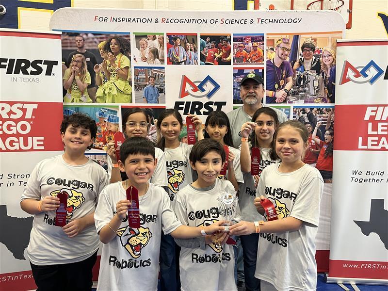Kids posing with teacher and ribbon at Robotics competition.