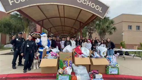 Operation Blue Santa; students and officers stand around toys that will be given to the community. 