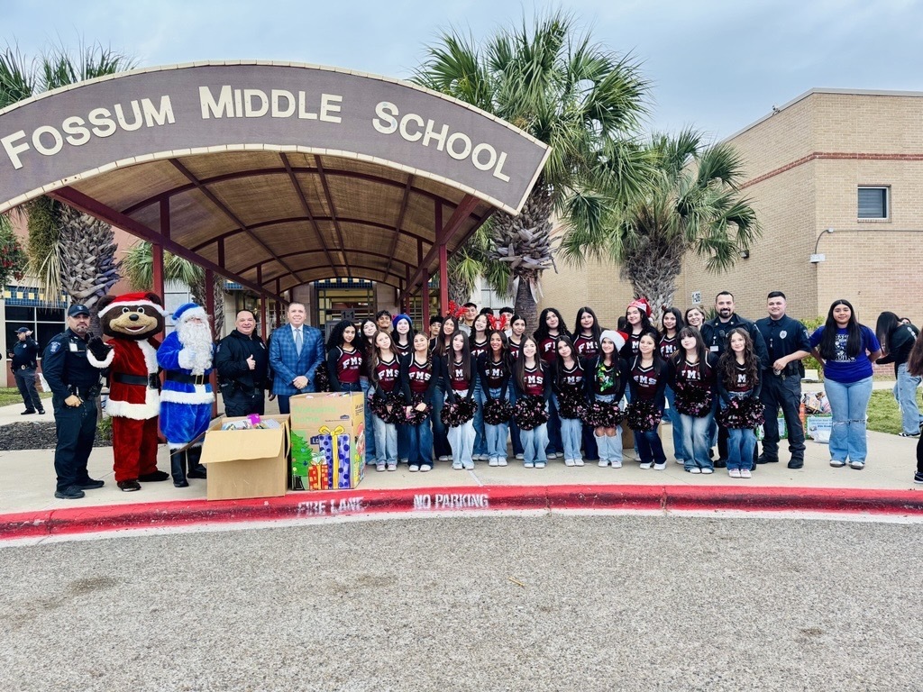 Operation Blue Santa; students and officers stand around toys that will be given to the community. 