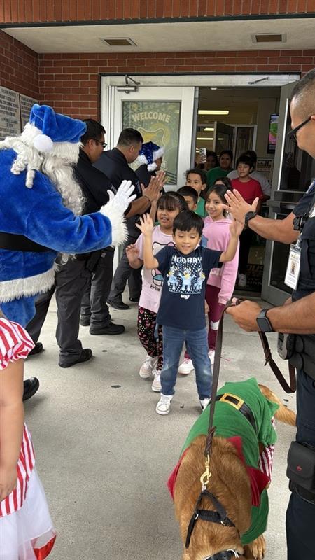 Kids exiting school excitedly while giving officers high fives.