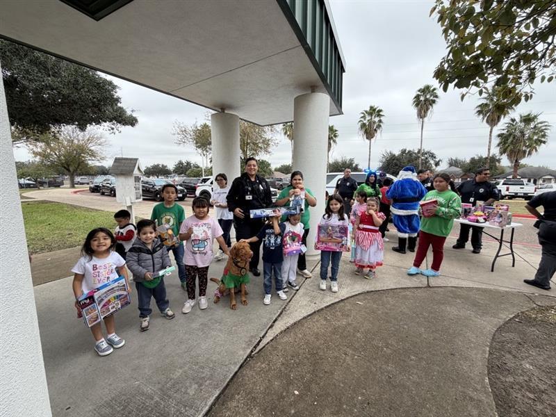 Kids posing with officer and toys.