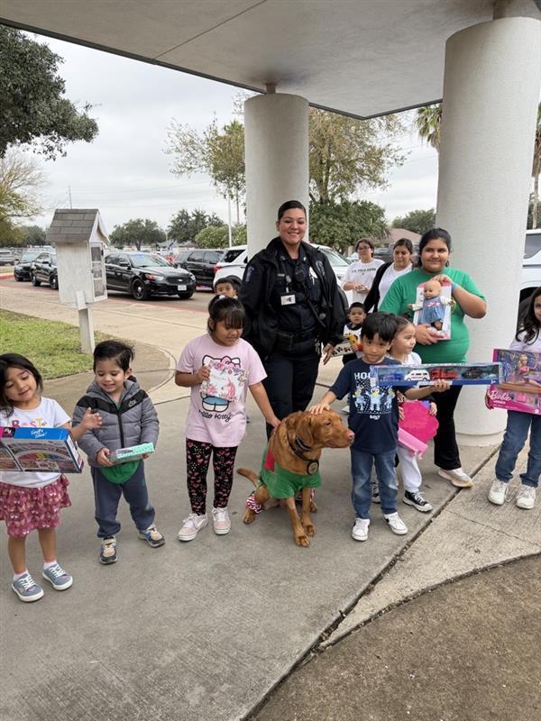 Kids posing with officer and toys.