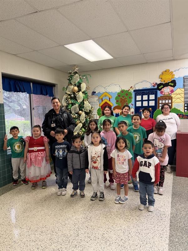 Kids posing with officer in front of Christmas tree.