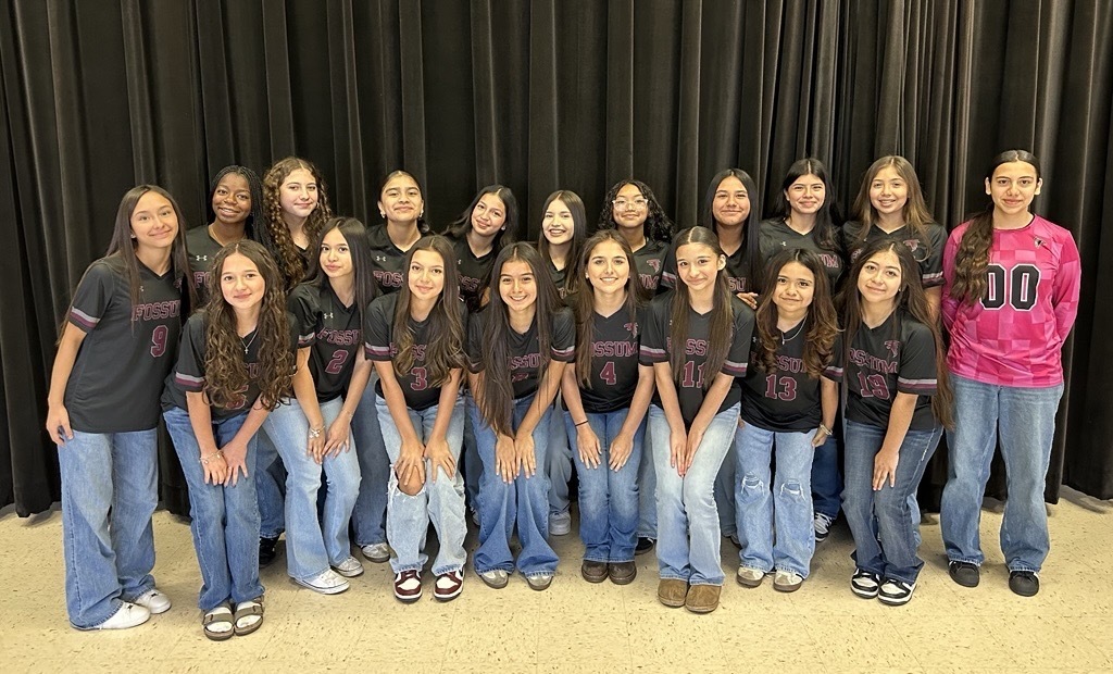Photo of 7th grade Lady Falcons soccer team in front of black curtain.