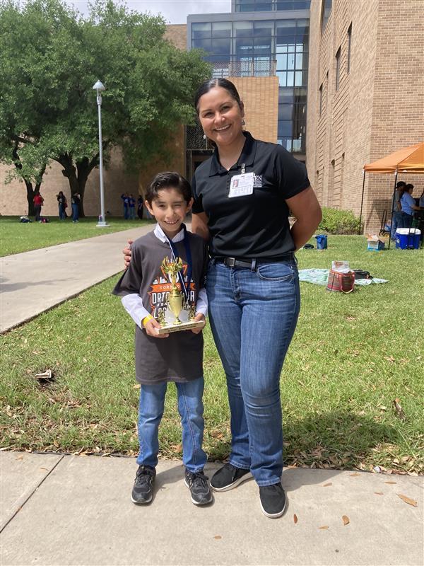 Kid and adult posing with trophy.