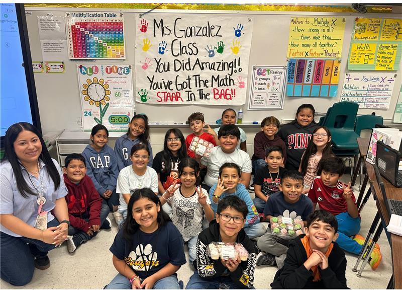 Kids posing in front of STAAR motivational poster.