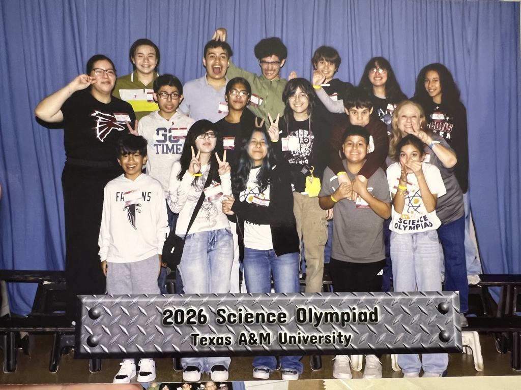 Fossum Middle School students and a chaperone pose together at the 2026 Science Olympiad at Texas A&M University. The group of approximately 15 students smiles and makes fun poses in front of a blue curtain backdrop.