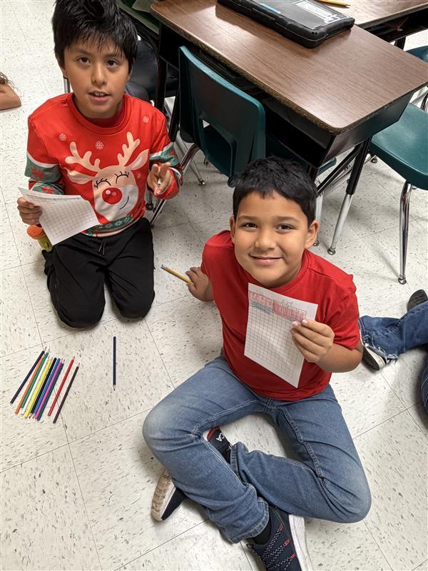 Kids posing with work in hand.