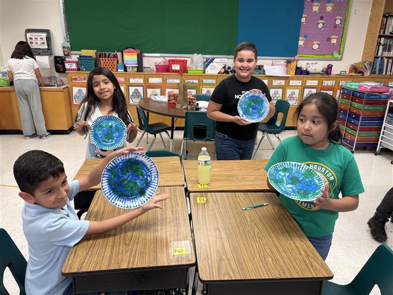Kids posing with finished product from Earth Day activity.