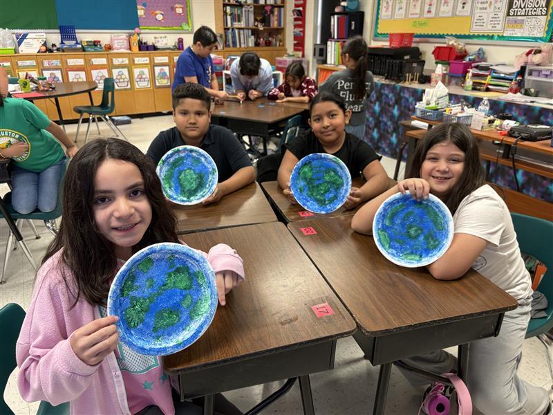 Kids posing with finished product from Earth Day activity.