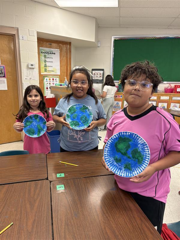 Kids posing with finished product from Earth Day activity.