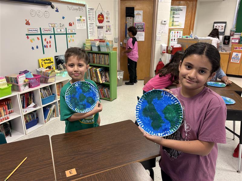 Kids posing with finished product from Earth Day activity.