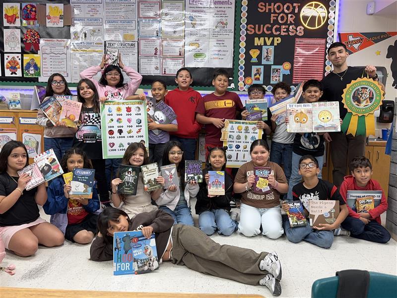Students posing with books, accelerated reader posters, and grade-level ribbon.