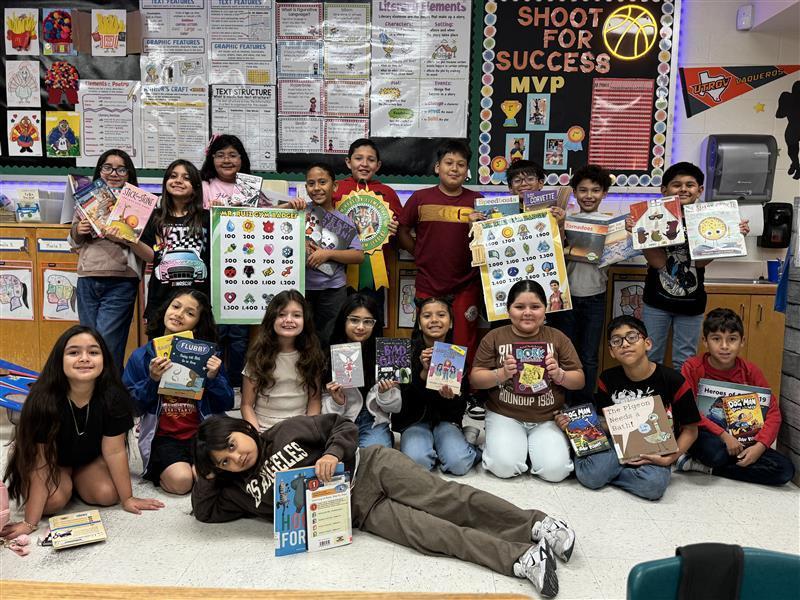 Students posing with books, accelerated reader posters, and grade-level ribbon.