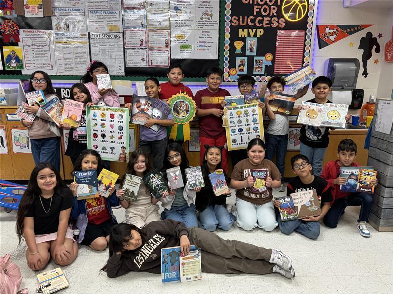 Students posing with books, accelerated reader posters, and grade-level ribbon.