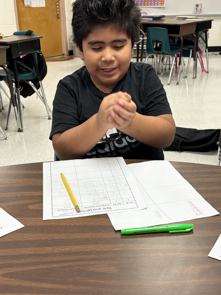 Student rolling a die to complete fact family practice.