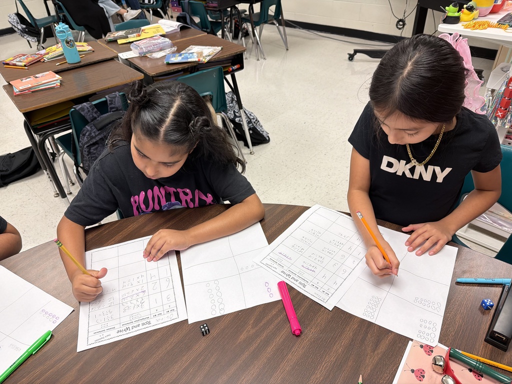 Students rolling a die to complete fact family practice.