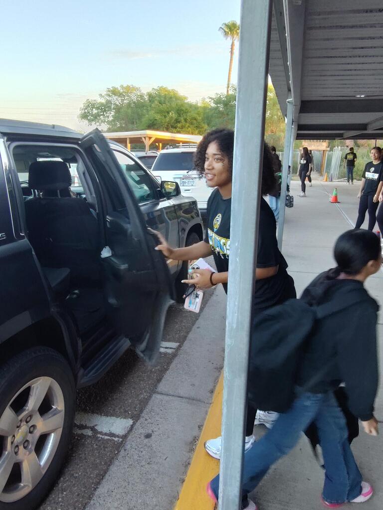 Volleyball player opening doors for student.