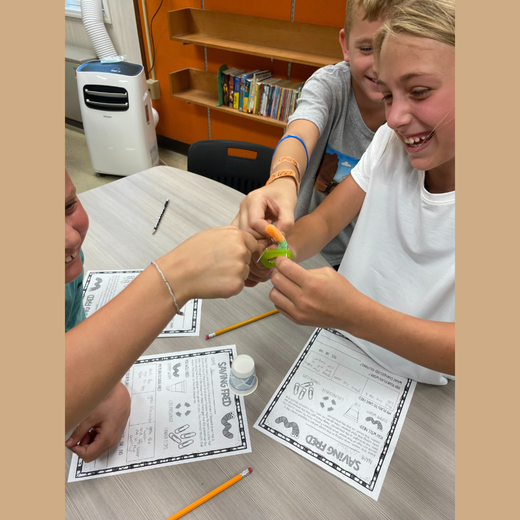 Elementary students putting a gummy worm through an Apple-O