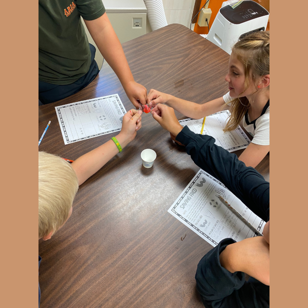 Elementary students playing with a gummy worm
